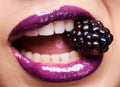 Woman lips closeup, purple lipstick with blackberry and makeup, shine and creativity with beauty. Fruit between female