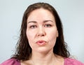 Woman with lips extended into a tube, portrait on grey background, emotions series