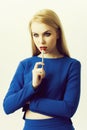 Woman with lipstick brush on red lips wearing blue dress