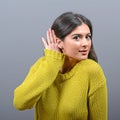 Woman listening with hand to ear concept against gray background Royalty Free Stock Photo