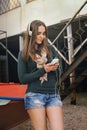 Woman listening music with cameraphone on an old pier beside the boat. Royalty Free Stock Photo