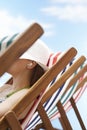 Woman Listening Music Through Earphones On Deckchair