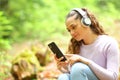 Woman listening music wathing phone content in a forest Royalty Free Stock Photo