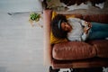 Young woman relaxing on sofa listening to music while lying on couch at home