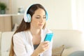 Woman listening to music at home with blue phone