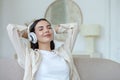 A woman listening to music in white headphones, closed her eyes, put her hands behind her head Royalty Free Stock Photo