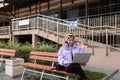 a woman listens to music in headphones with a laptop in her hands against the backdrop of stairs to a residential