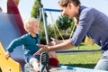 Woman and little boy chuting down slide at playground Royalty Free Stock Photo