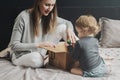 Woman and little child playing with big cardboard box. Mother putting things into package