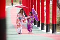 Woman and little girl in kimono holding umbrella walking into at the shrine red gate, in Japanese garden Royalty Free Stock Photo