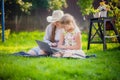 Woman and little girl laying on the spring flower field outdoors - having fun using a laptop Royalty Free Stock Photo