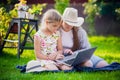 Woman and little girl laying on the spring flower field outdoors - having fun using a laptop Royalty Free Stock Photo