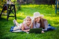 Woman and little girl laying on the spring flower field outdoors - having fun using a laptop Royalty Free Stock Photo