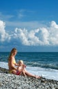 Woman and little girl sit on seacoast