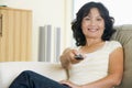 Woman in living room holding remote control