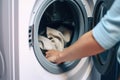 Woman loading clothes into washing machine in laundromat, closeup. Generative AI