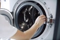 Woman loading clothes into washing machine in laundromat, closeup. Generative AI