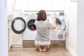 Woman Loading Dirty Clothes In Washing Machine For Washing In modern Utility Room Royalty Free Stock Photo