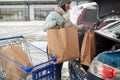 Woman loading food from shopping cart to car trunk Royalty Free Stock Photo