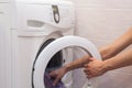 Woman loading laundry to the washing machine.