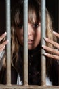 Woman locked in a block looking through the bars