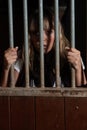 Woman locked in a block looking through the bars