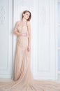 Woman in long beige dress in interior. Beauty