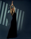 Woman in long Black Dress perform on Art Stage. Elegant Lady in evening Gown over striped spotlight Background. Beautiful dancing Royalty Free Stock Photo