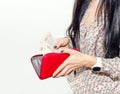 Woman with long black hair puts paper money in a red purse Royalty Free Stock Photo