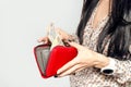 Woman with long black hair puts paper money in a red purse Royalty Free Stock Photo