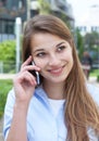 Woman with long blond hair flirting at phone outside Royalty Free Stock Photo