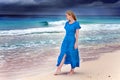 The woman in a long blue dress goes on the sea coast Royalty Free Stock Photo