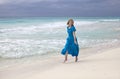 Woman in a long blue dress goes on the stormy sea coast Royalty Free Stock Photo