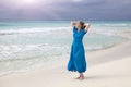 Woman in a long blue dress goes on the stormy sea coast Royalty Free Stock Photo