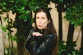 Woman with long brown hair blowing kisses with her hand, with background of trees in a garden Royalty Free Stock Photo