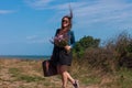 Woman with long brown hair in denim jacket, black skirt, vintage suitcase, flowers bouquet off-road. Lifestyle photo Royalty Free Stock Photo