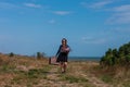 Woman with long brown hair in denim jacket, black skirt, vintage suitcase, flowers bouquet off-road. Lifestyle photo Royalty Free Stock Photo