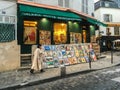 Woman in long coat walks past print shop on Montmartre, Paris Royalty Free Stock Photo