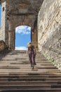 Woman in a long dress is climbing the steps of the abbey of Saint Antoine