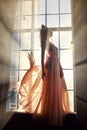 Woman in long dress stands at window in sunlight. Fairy Princess Royalty Free Stock Photo