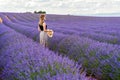 Woman in long dress and sunglasses standing in purple blooming lavender flowers field