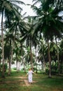 Woman in long dress walk under palm trees. Romantic island vacation