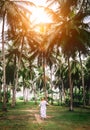 Woman in long dress walk under palm trees. Romantic island vacat