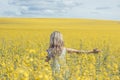 Woman with long hair back view, yellow rapeseed canola field enjoying nature and sunlight. Royalty Free Stock Photo