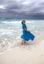 Woman with long hair fluttering in the wind in a blue dress on the shore of a stormy sea on a sandy beach Cuba, Varadero Royalty Free Stock Photo