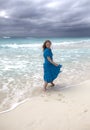 Woman with long hair fluttering in the wind in a blue dress on the shore of a stormy sea on a sandy beach Cuba, Varadero Royalty Free Stock Photo