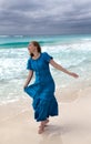 Woman with long hair fluttering in the wind in a blue dress on the shore of a stormy sea on a sandy beach Cuba, Varadero Royalty Free Stock Photo