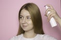 Woman with long hair holds a spray bottle in a white bottle and sprays it on her hair. Hair care product, body care Royalty Free Stock Photo