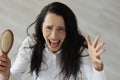 Woman with long hair screaming and holding comb in her hands Royalty Free Stock Photo