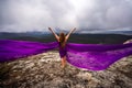 A woman with long hair is standing in a purple flowing dress with a flowing fabric. On the mountain against the Royalty Free Stock Photo